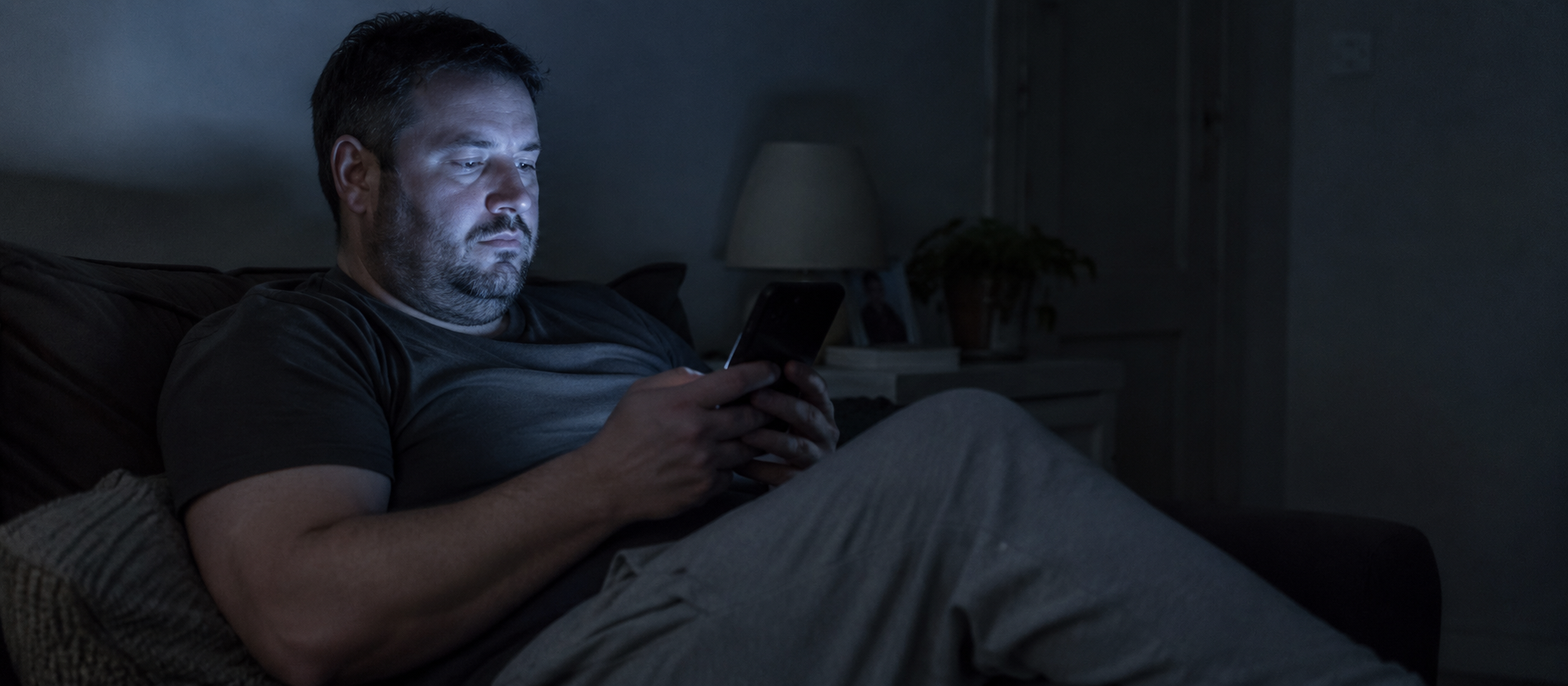 Hombre en sofá mirando el móvil de noche